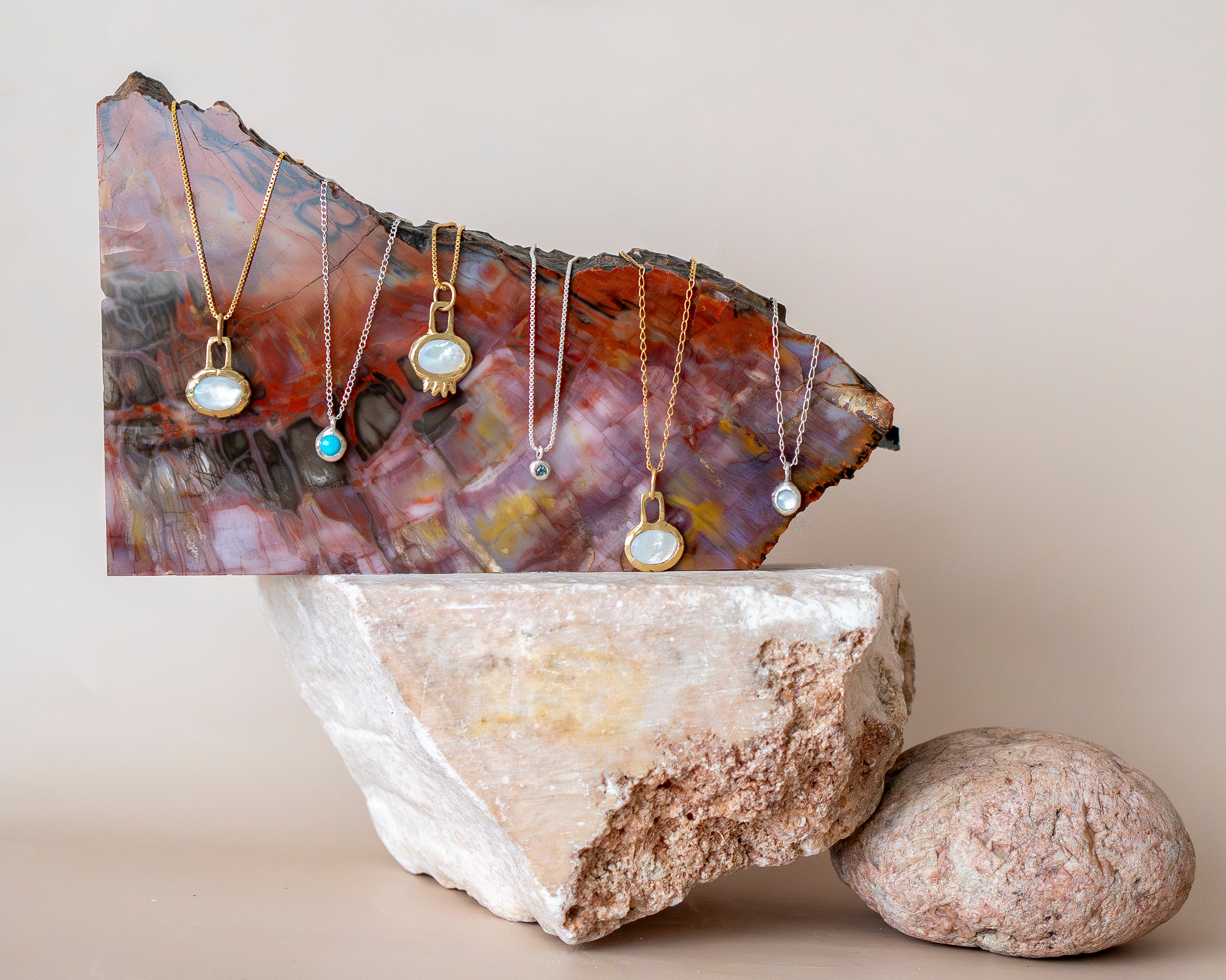 Necklaces displayed on a decorative stone surface with a neutral background