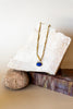 Necklace with a blue pendant on a white stone surface