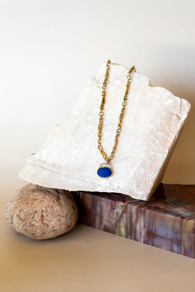 Necklace with a blue pendant on a white stone surface